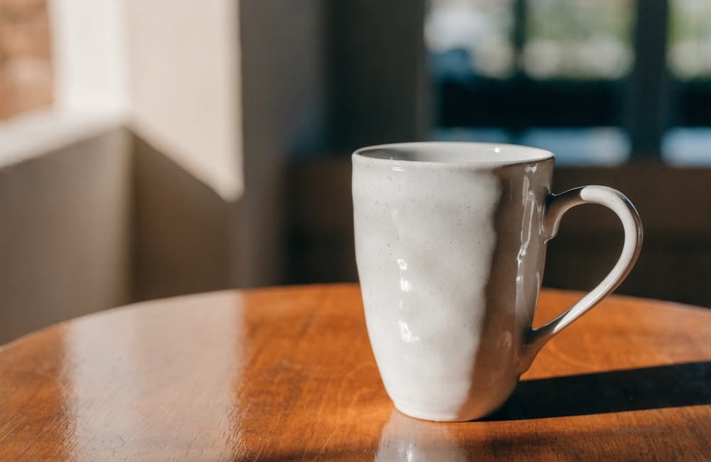 Product photo of a ceramic mug on a wooden table in natural light