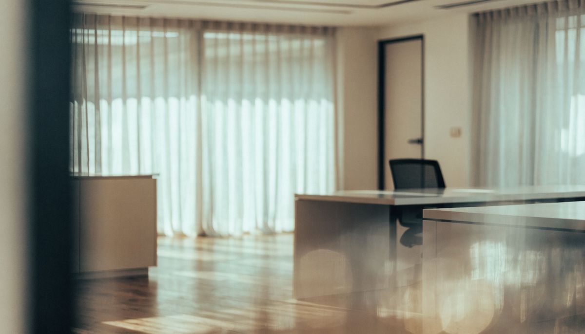 A modern minimalist office interior with floor-to-ceiling windows and warm wood tones