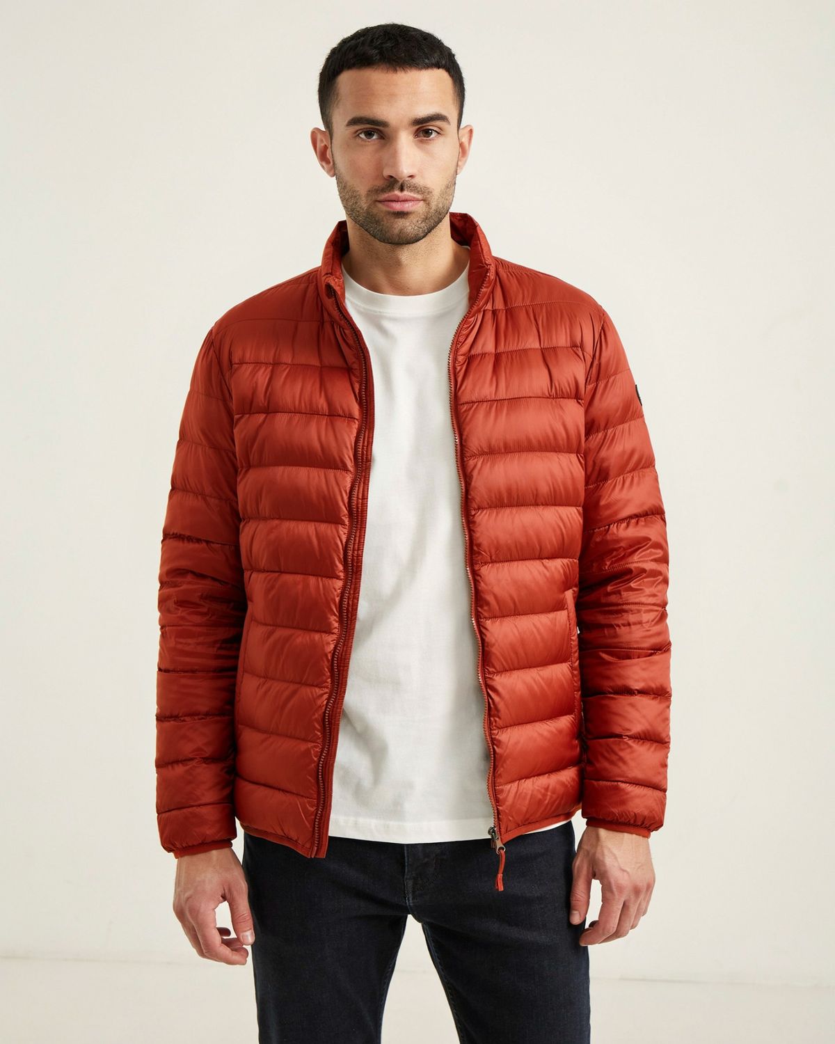 The same man and pose with the puffer jacket in deep rust orange