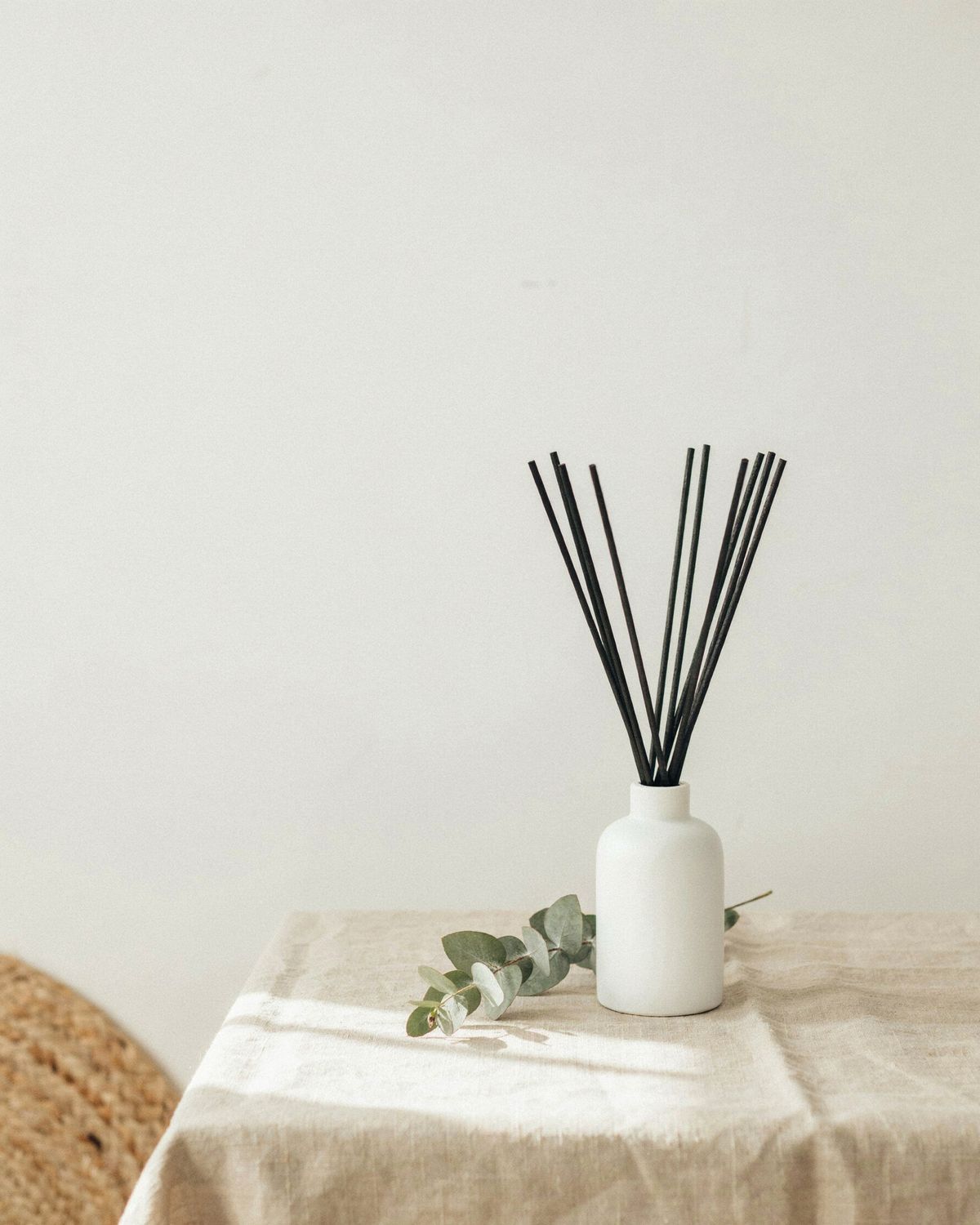 The same diffuser placed low in the frame, with a plain warm white wall filling the top of the image