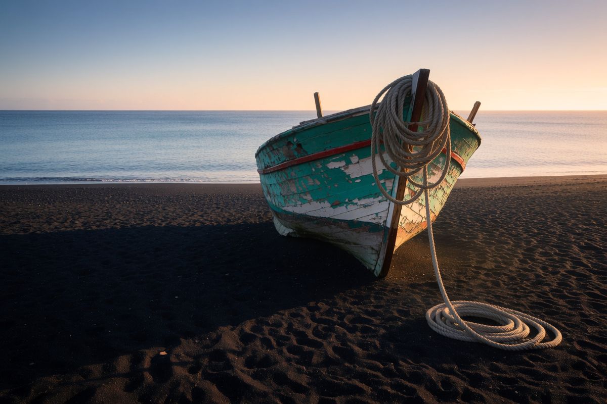 A fishing boat on black sand at dawn