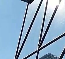 A close-up crop of dark diagonal beams against a bright sky, each beam outlined by a pale white line