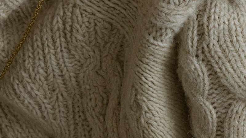 A 100 percent crop of the sweater showing individual cable stitches and fiber texture