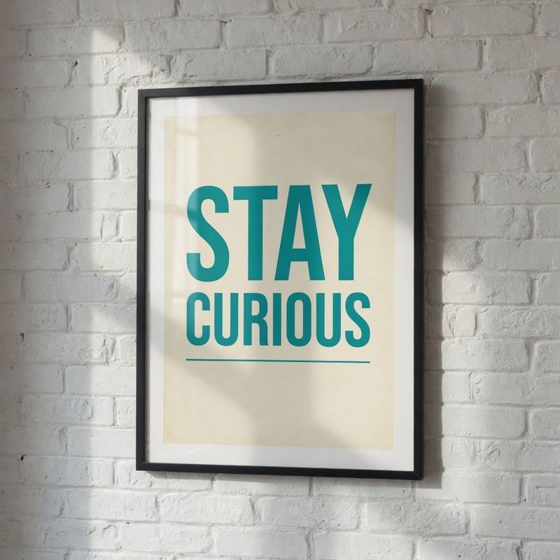 The same framed poster on a white brick wall now reading STAY CURIOUS in teal letters