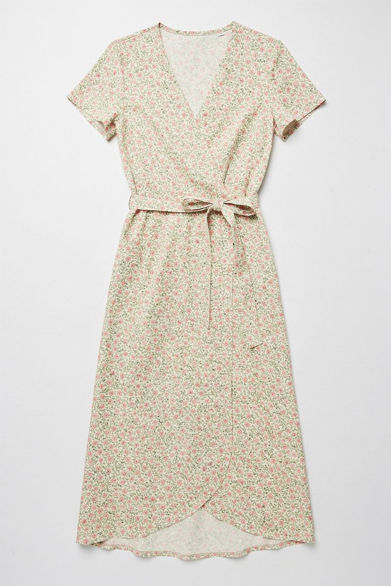 Flat-lay of a midi-length floral wrap dress with small pink and green flowers on a cream background