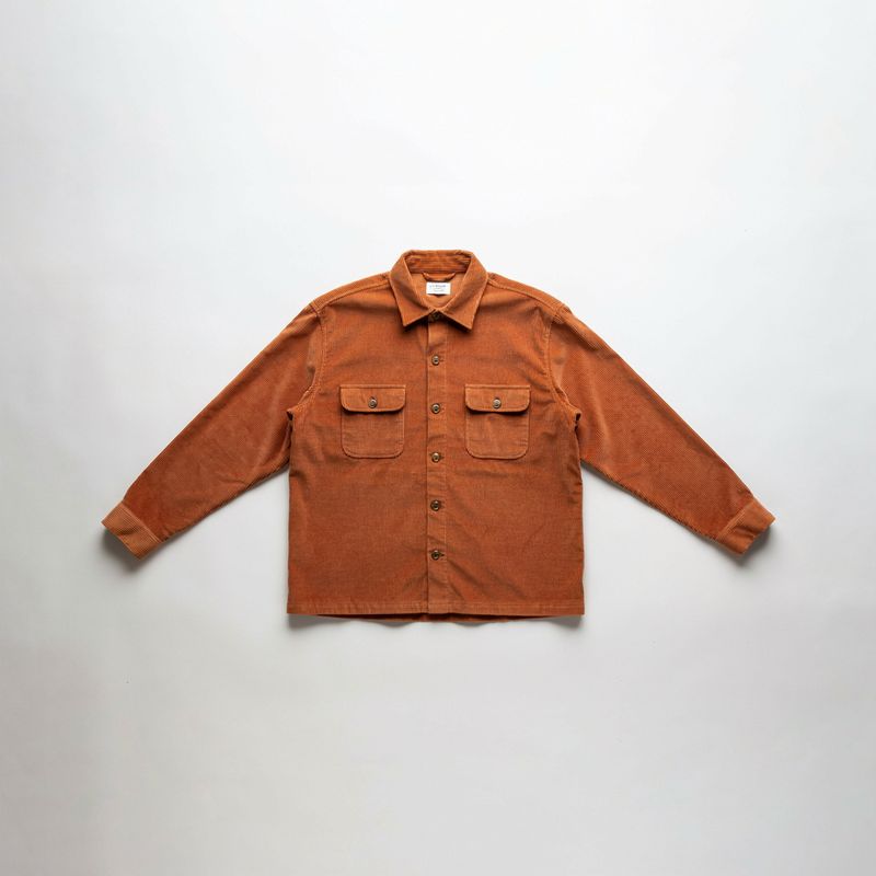 A rust orange corduroy overshirt laid flat on white