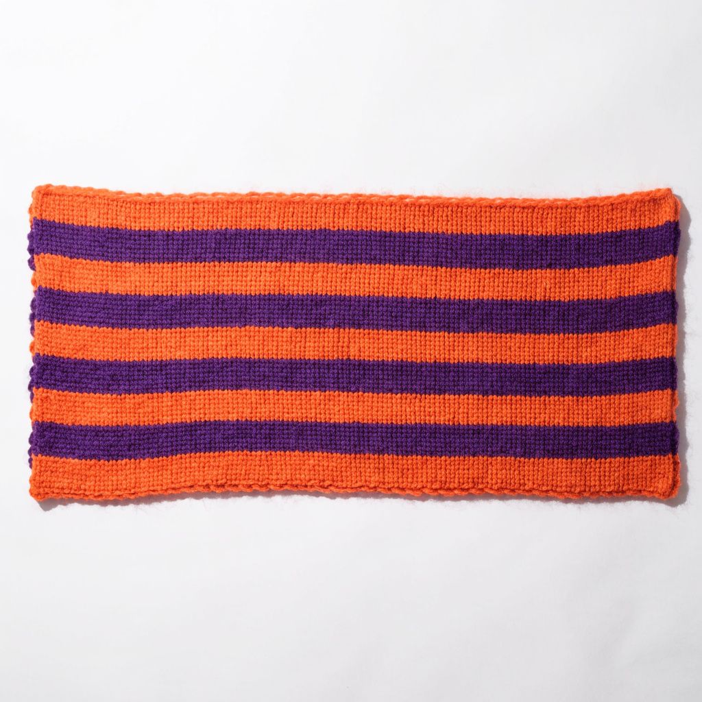 An orange and purple striped knit scarf