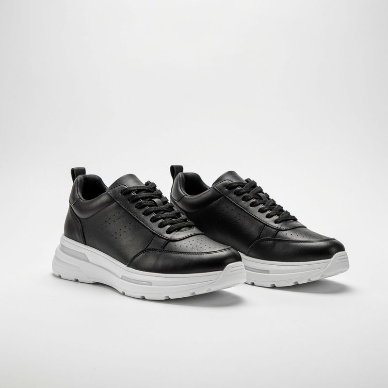 A pair of chunky black leather sneakers with white soles on white