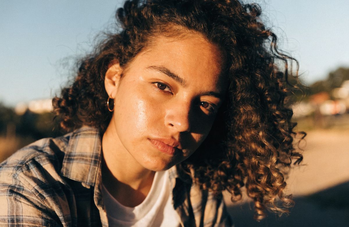 A cinematic portrait of a woman in golden hour light, wind moving through her hair, shot with shallow depth of field