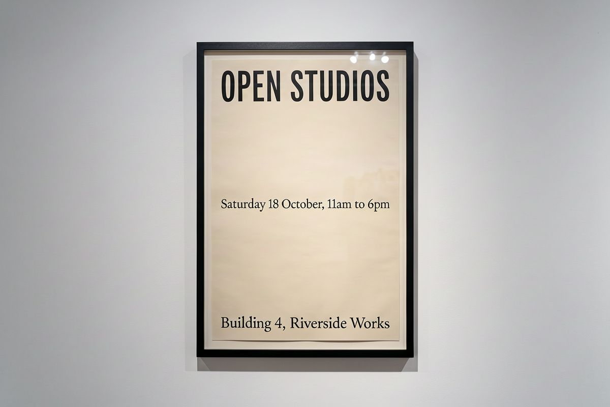 A framed poster on a gallery wall reading OPEN STUDIOS with a date line and a venue line beneath