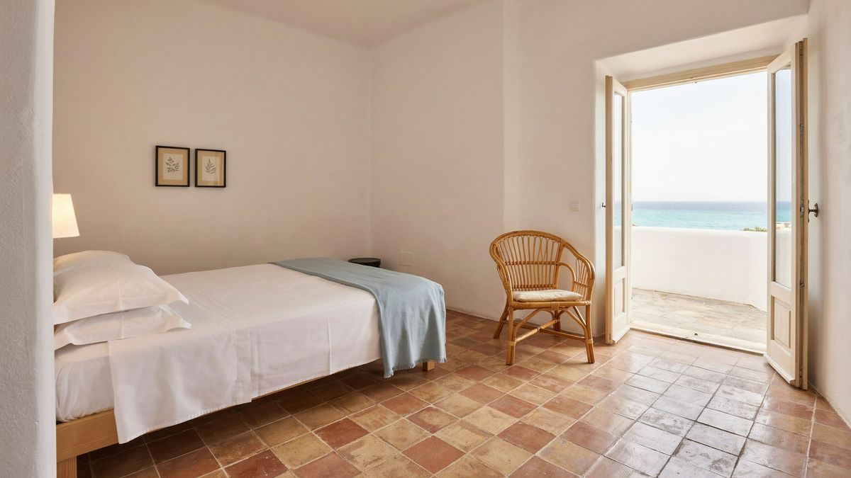 The detailed hotel room prompt rendered with Magic Prompt off, with the bed on the left, the rattan chair on the right and open doors to a sea-view balcony