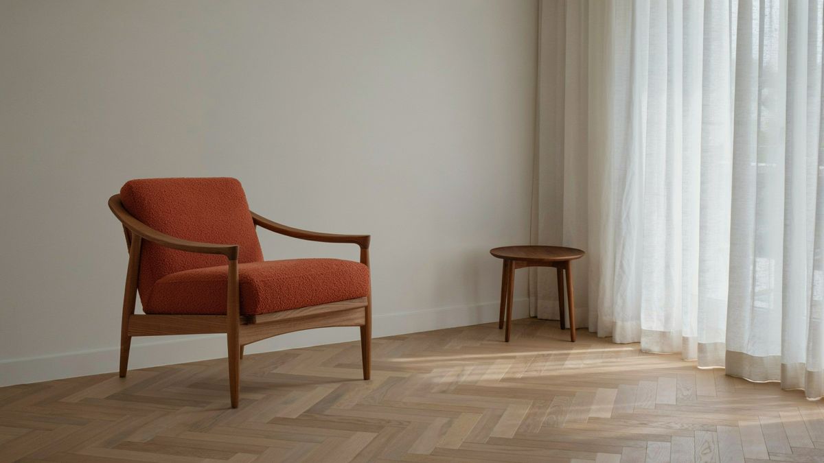 The living room corner with a mid-century walnut armchair upholstered in terracotta boucle next to the side table