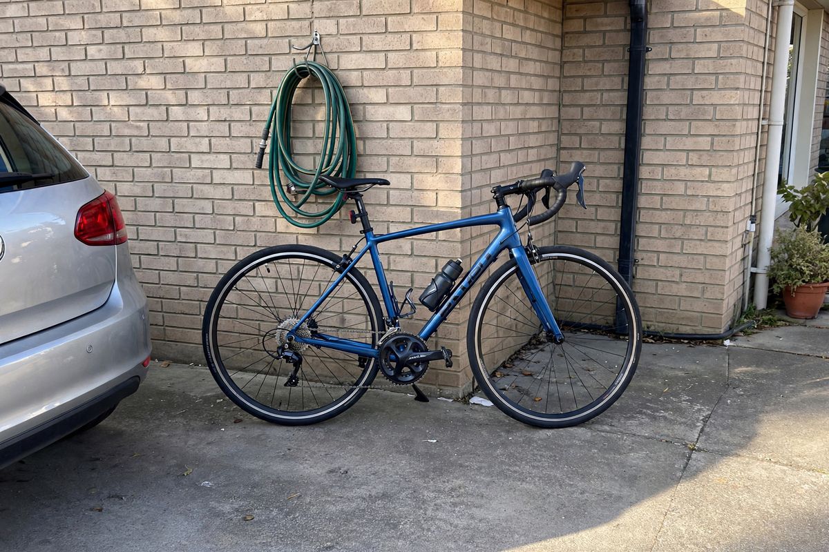The same driveway shot with the green wheelie bin gone and the brick wall continuous behind the rear wheel, the car and the hose still in frame