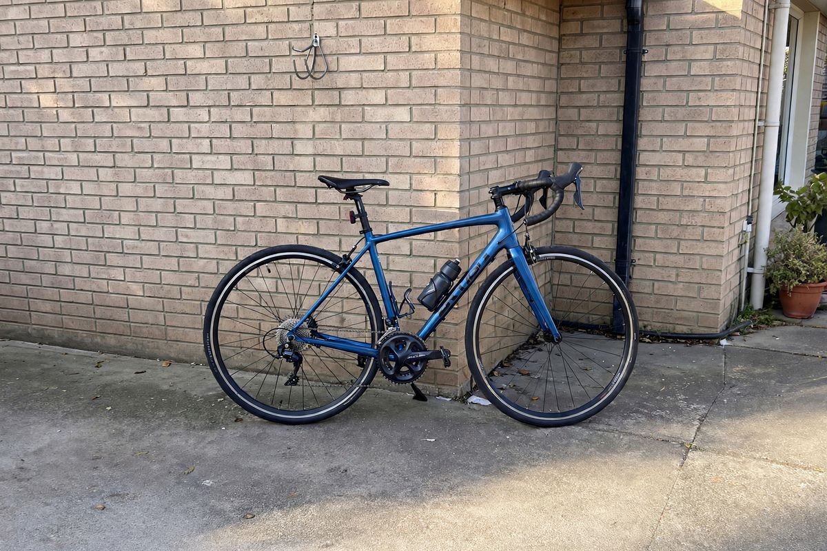 The same shot with the coiled hose gone from the wall, leaving plain brick above the handlebars and only the bike on the driveway