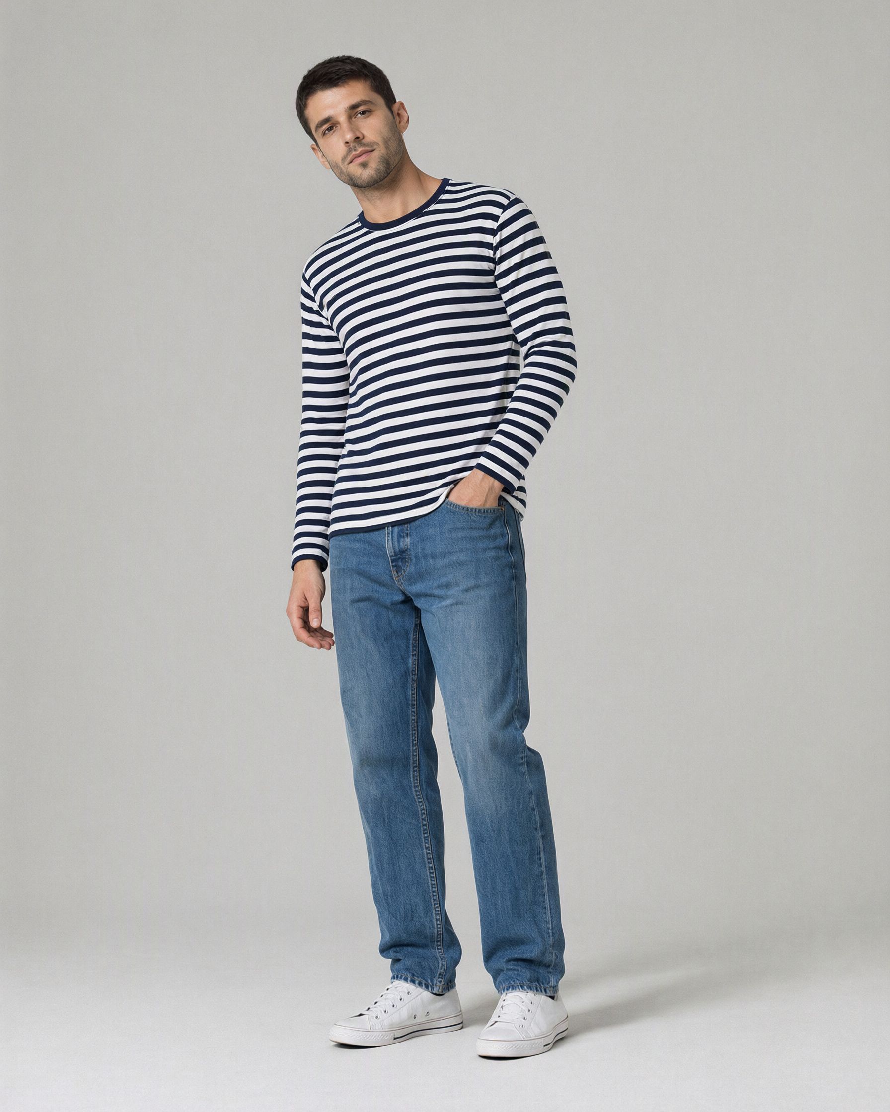 The same man now wearing a navy and white striped long-sleeve top with the same jeans and sneakers