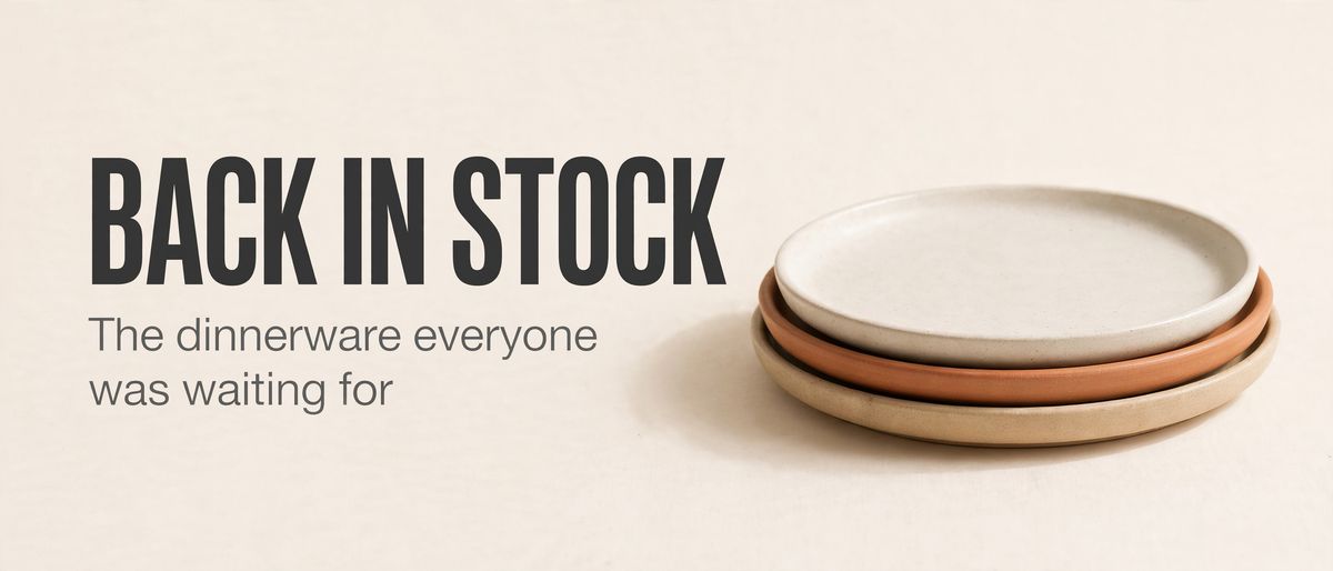 A wide banner on an off-white background with BACK IN STOCK in heavy charcoal capitals on the left, The dinnerware everyone was waiting for on the line beneath it, and a stack of three ceramic plates in sand, clay and off-white on the right