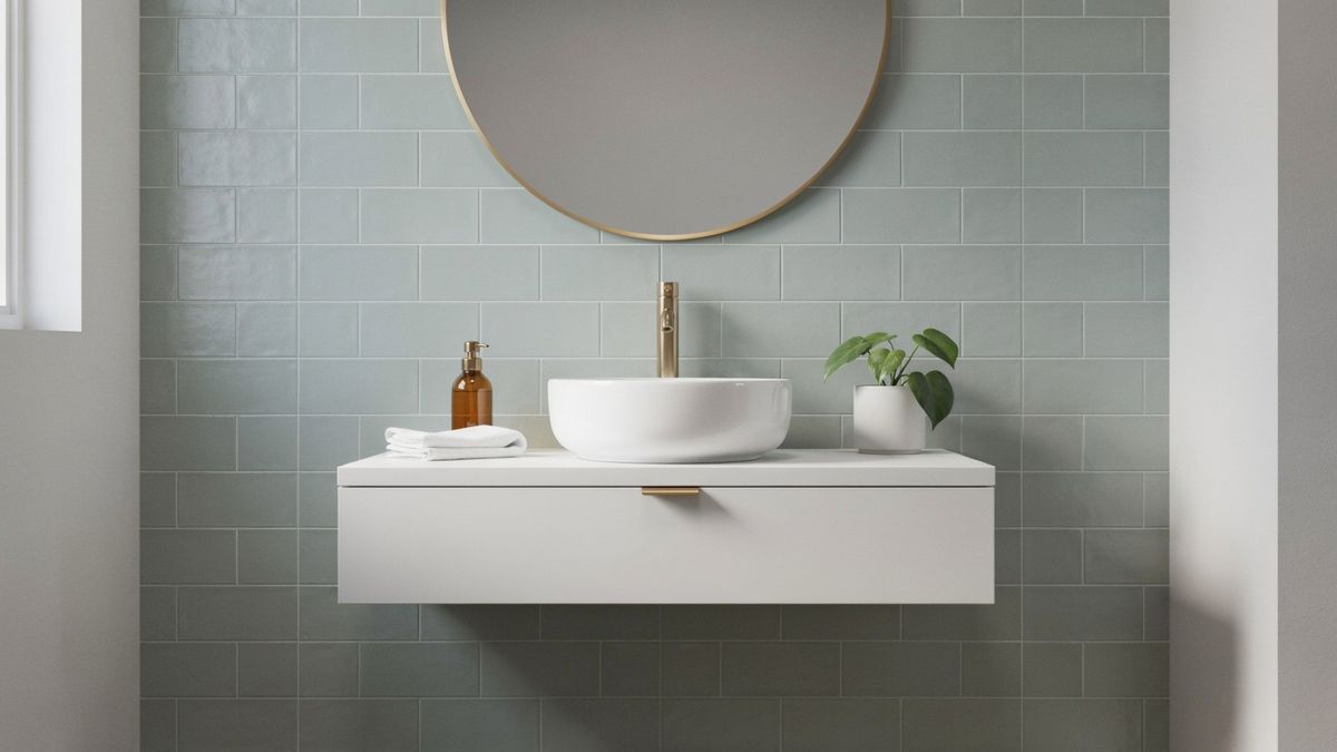 The same bathroom with a round brass-framed mirror above the sink in place of the rectangular one