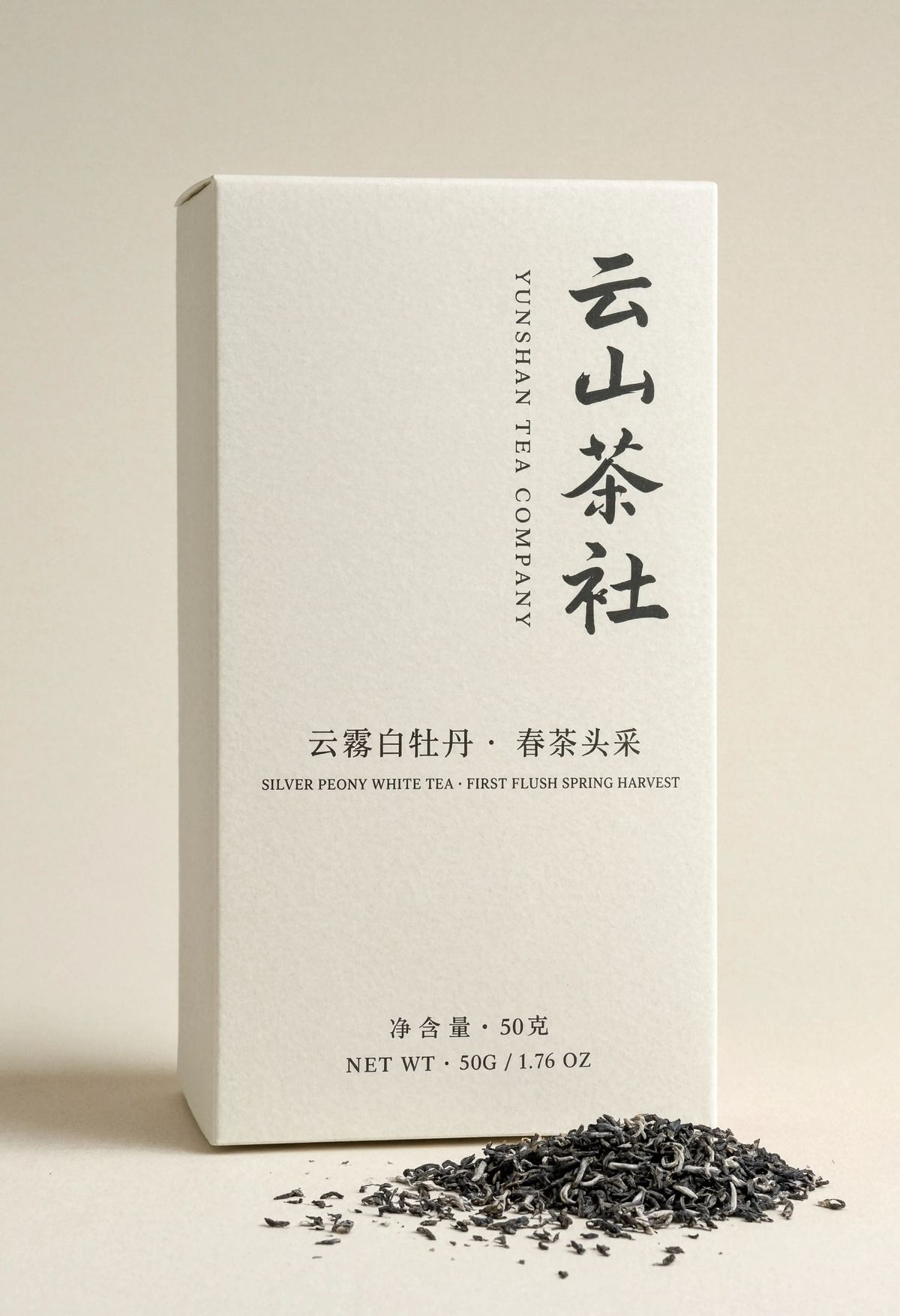 A Simplified Chinese and English tea packaging box on a warm cream backdrop, with the vertical Chinese brand name 云山茶社 in warm charcoal ink brush style running down the upper right of the box, the English brand name YUNSHAN TEA COMPANY in tracked serif capitals in a narrow column to its left, tea variety 云雾白牡丹 and SILVER PEONY WHITE TEA across the middle, and dual-language weight lines at the base
