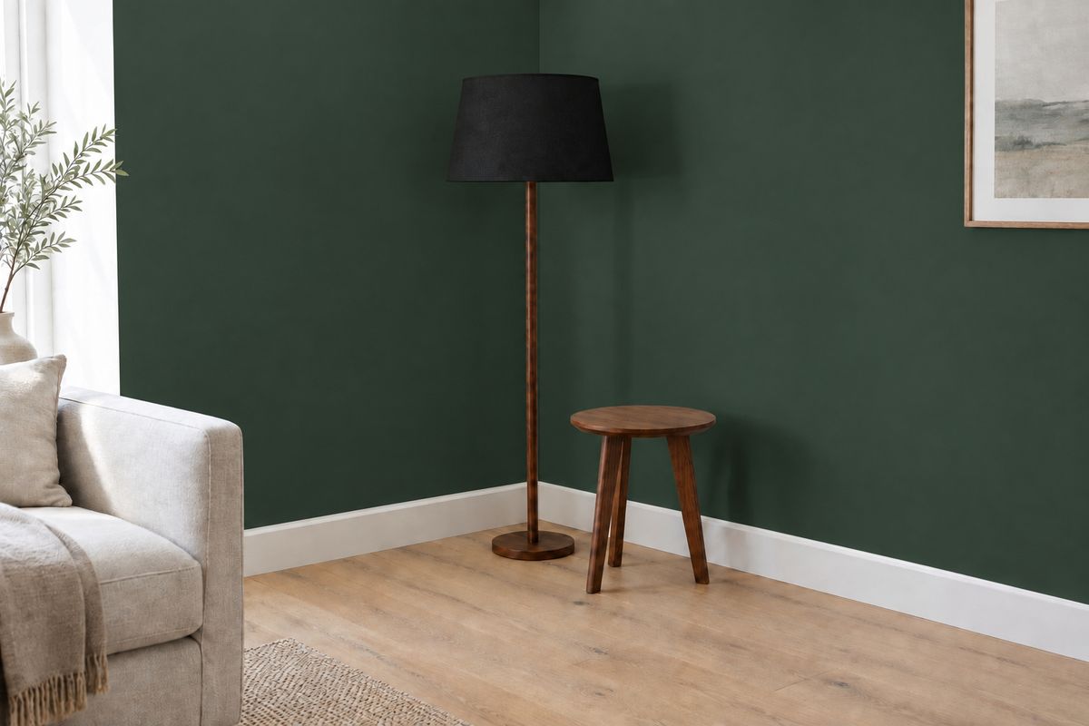 The same corner with the matte black lampshade and the wall repainted deep forest green