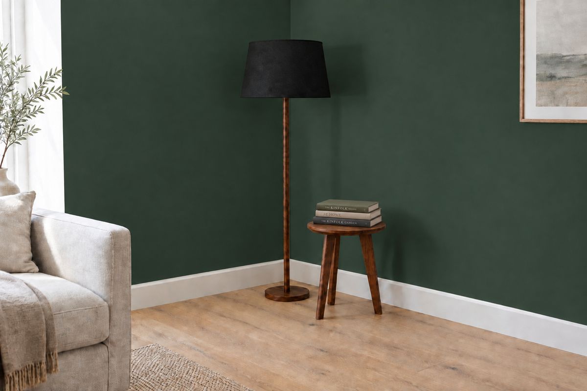 The same corner with the matte black shade and green wall, now with a stack of three hardback books lying on the side table