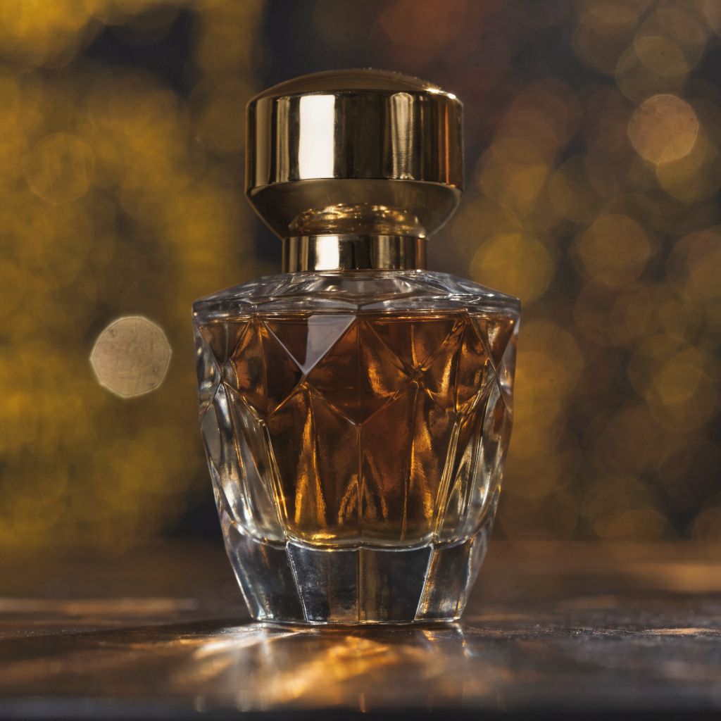 A luxury perfume bottle in amber and gold tones on a deep navy background