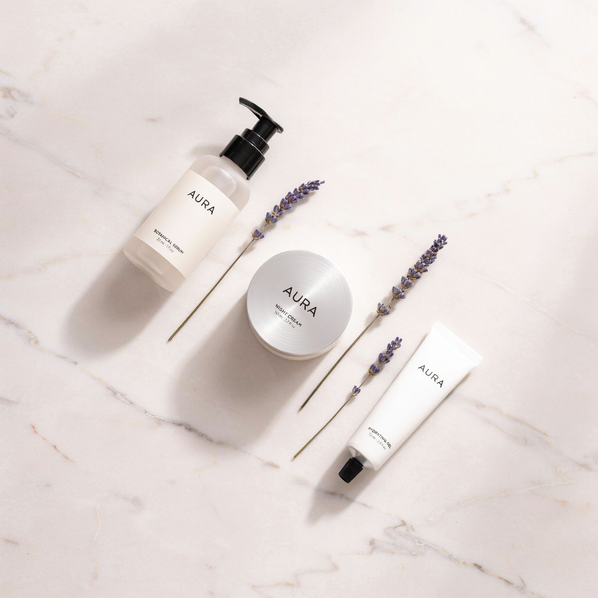 A skincare flat lay on pink marble at low quality, with a pump bottle, a jar and a tube labeled AURA