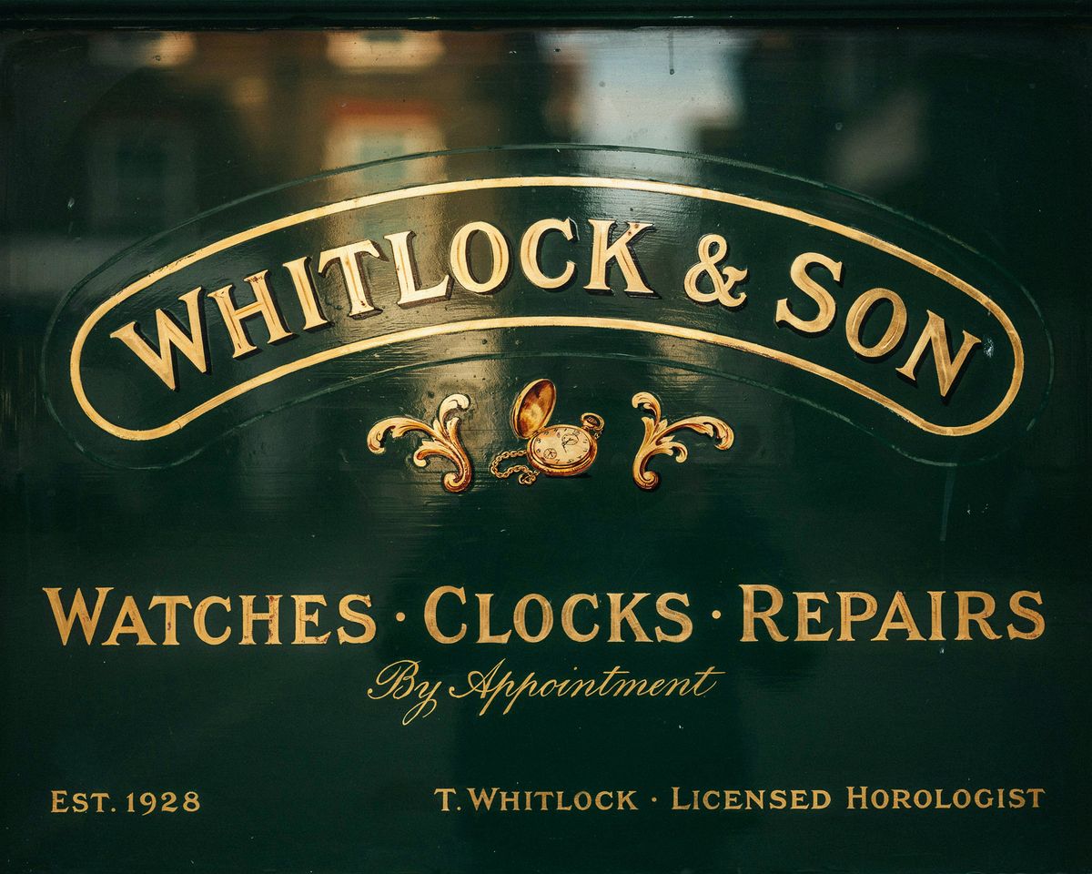 The same watchmaker's shopfront window at QUALITY quality, with sharp gold-leaf brush-stroke detail, a crisp proprietor line, and a finely reflected brick street behind the glass