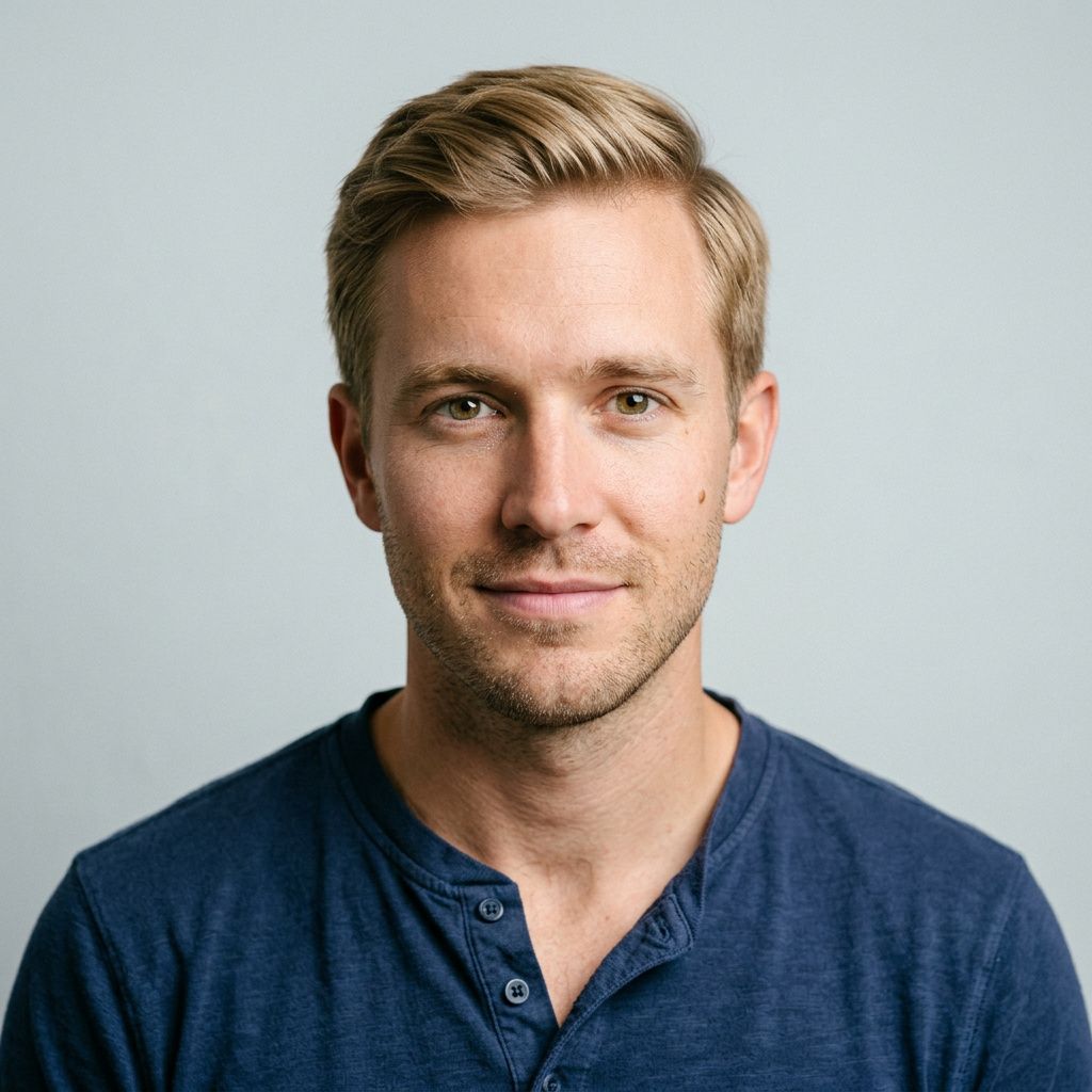 A photoreal chest-up studio portrait of a man in his early thirties with sandy blond hair, hazel-green eyes, and a navy henley shirt, facing the camera directly against a plain pale grey background
