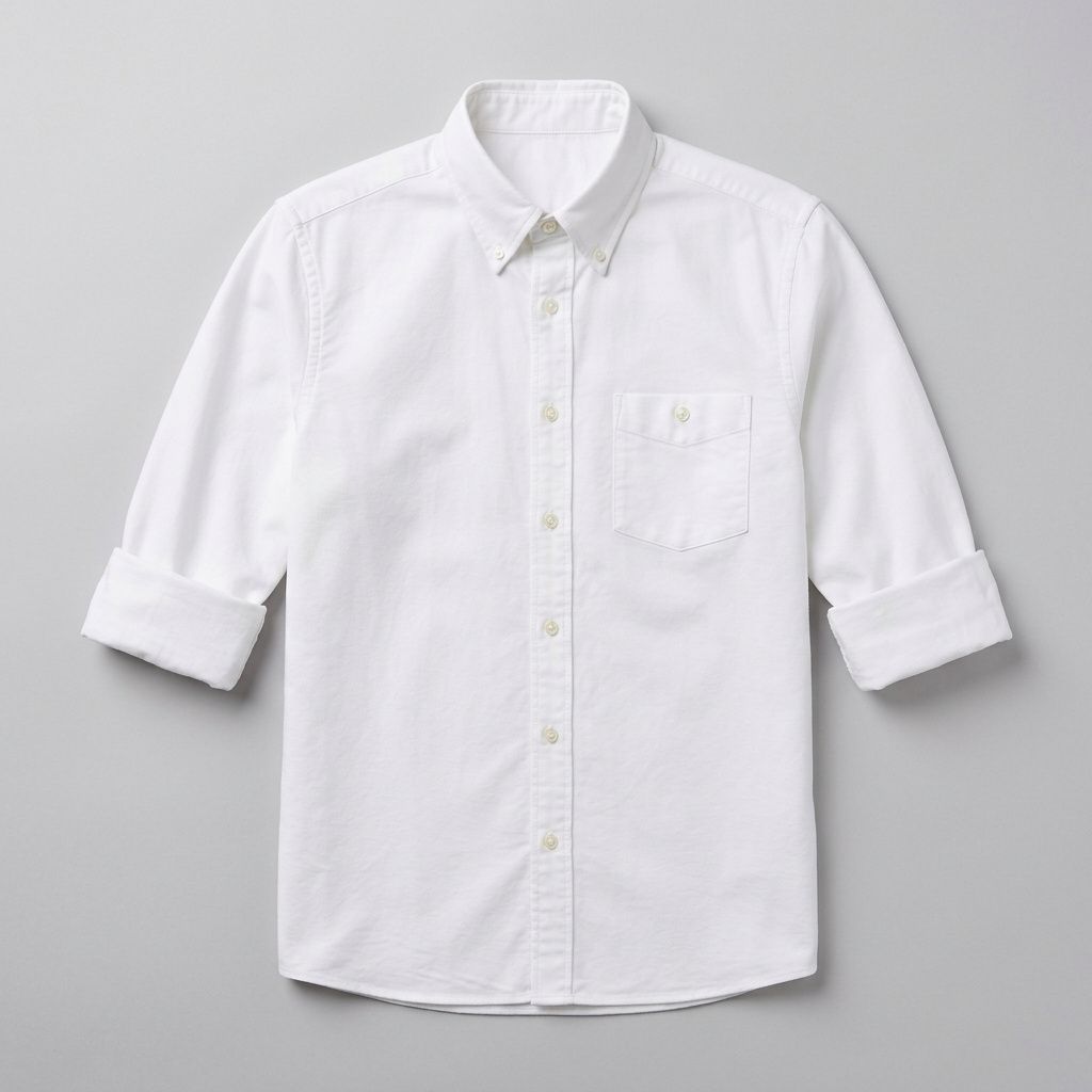 Flat-lay product photograph of a crisp white oxford button-down shirt with sleeves rolled to the elbows, on a plain pale grey background