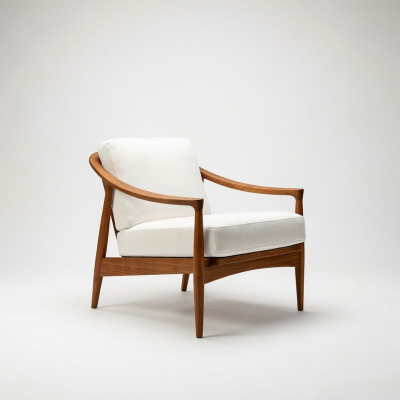 A mid-century armchair with a curved walnut frame and white cushions on white
