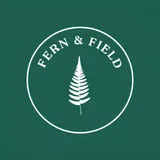 A round white fern badge with the words FERN & FIELD on a forest green background