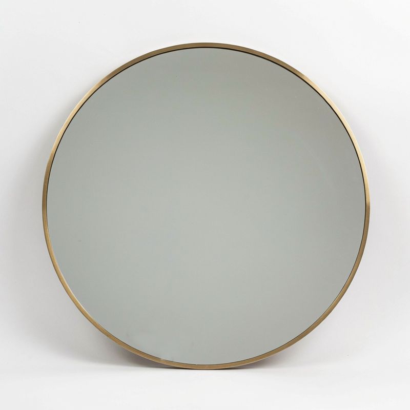 A round mirror with a thin brushed brass frame on white