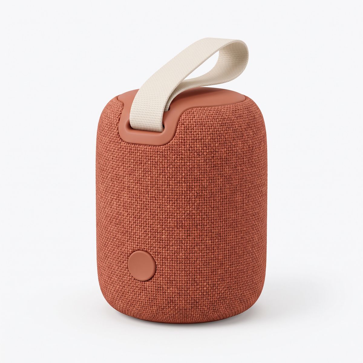 A compact portable speaker in terracotta woven fabric with a cream carry strap and a single round button, on a white background