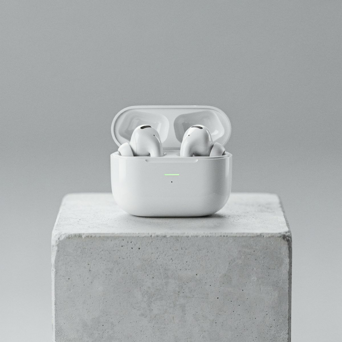 White wireless earbuds in an open charging case on a light gray concrete block