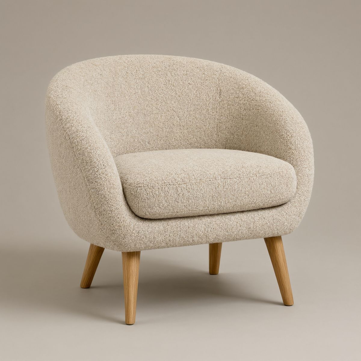 An oatmeal boucle armchair with a rounded shell back and tapered oak legs on a plain warm grey backdrop