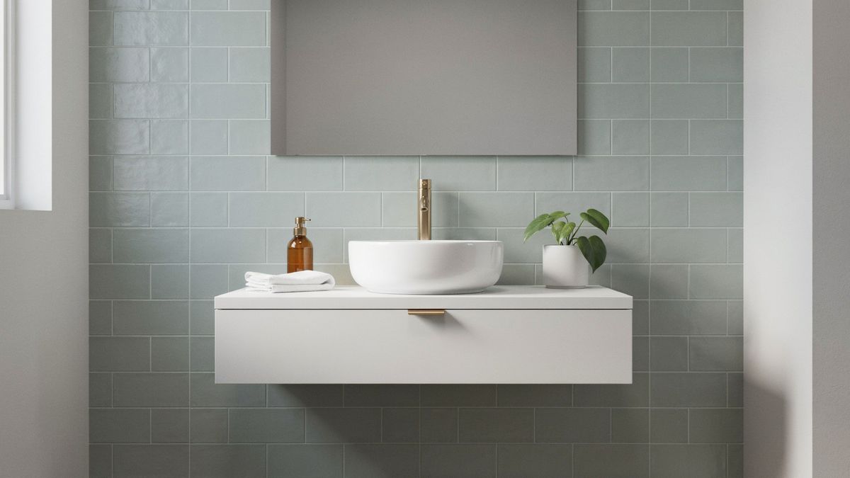 A modern bathroom with a white floating vanity, a vessel sink, a brass faucet and a rectangular mirror on a sage green tiled wall, with the masked area over the mirror highlighted