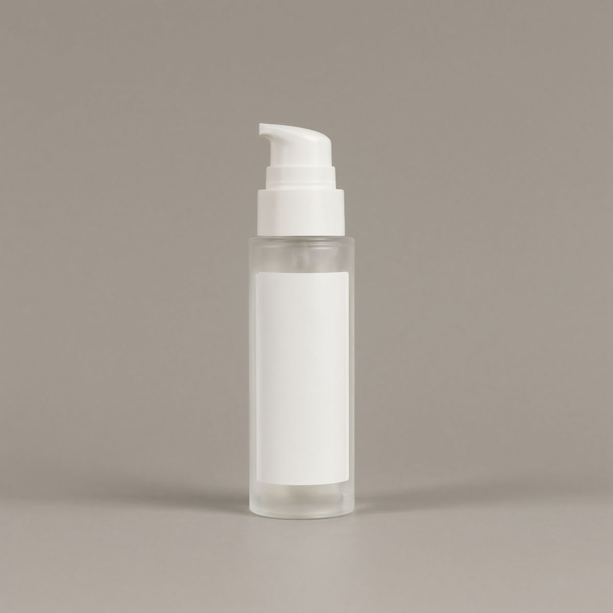 A frosted clear glass skincare bottle with a matte white pump on a plain warm grey backdrop