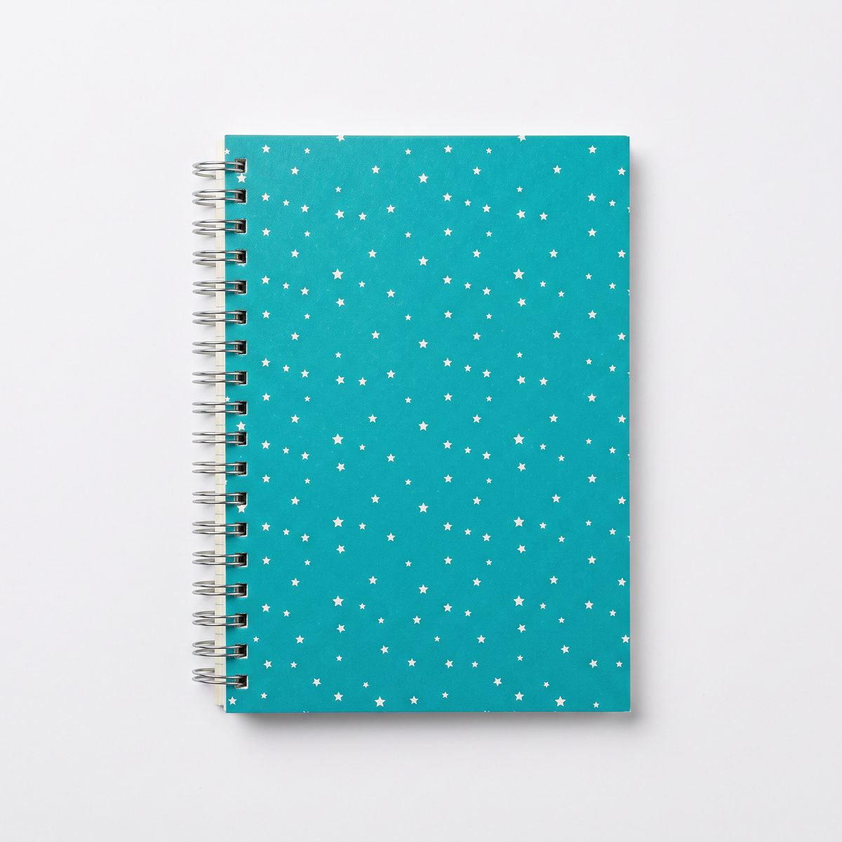 A spiral notebook with a teal cover patterned with small white stars on white