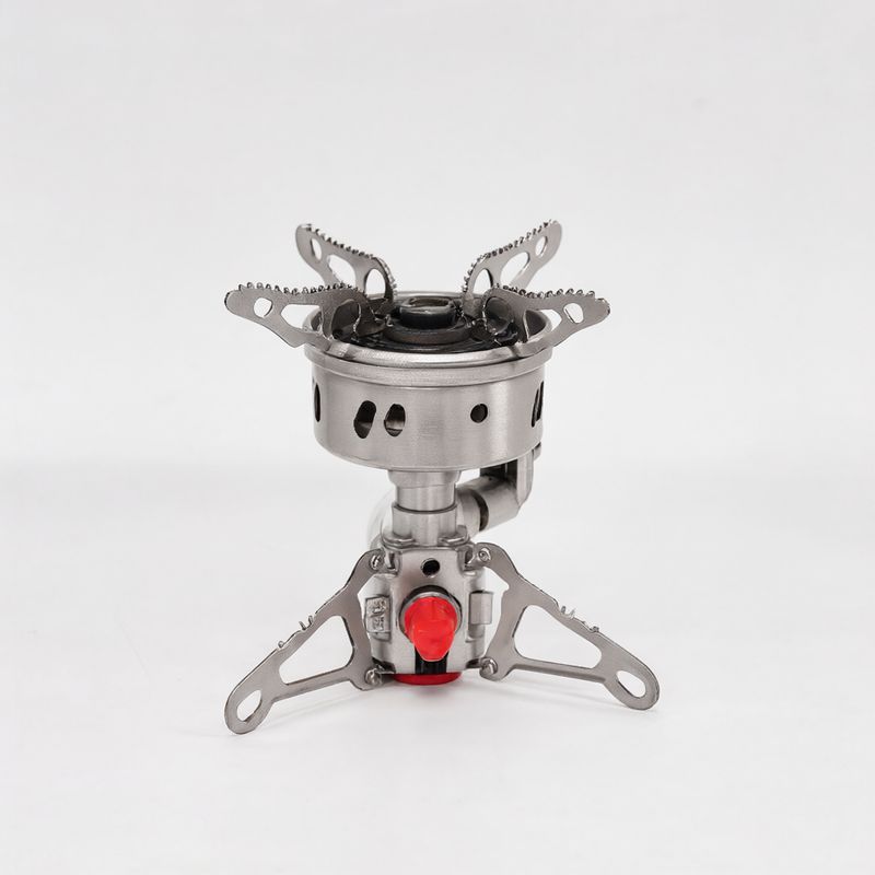 A brushed steel folding backpacking stove with three pot supports and a red valve on white
