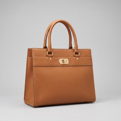 A tan pebbled-leather tote handbag on a grey studio background, soft and low resolution