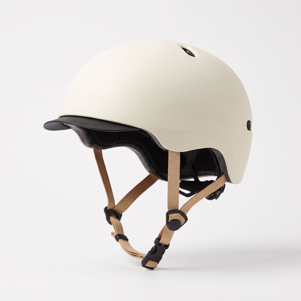 A matte cream urban cycling helmet with a short black visor and tan straps on white
