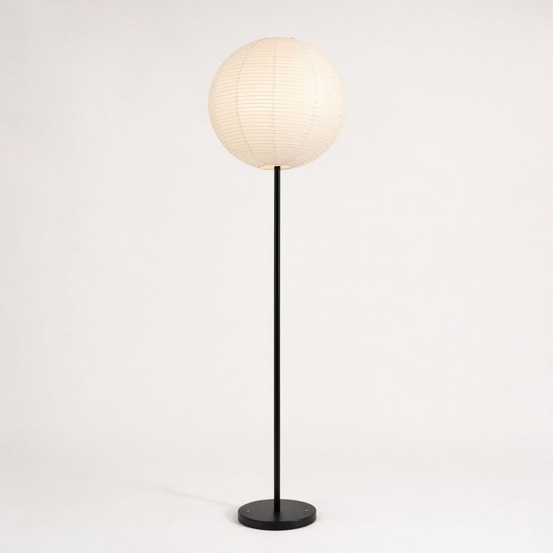 A tall floor lamp with a black steel stem and a pleated paper globe shade on white