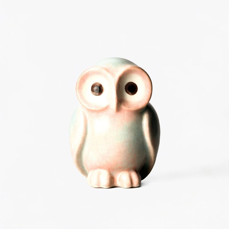 A glazed ceramic owl figurine centered on a plain gray background