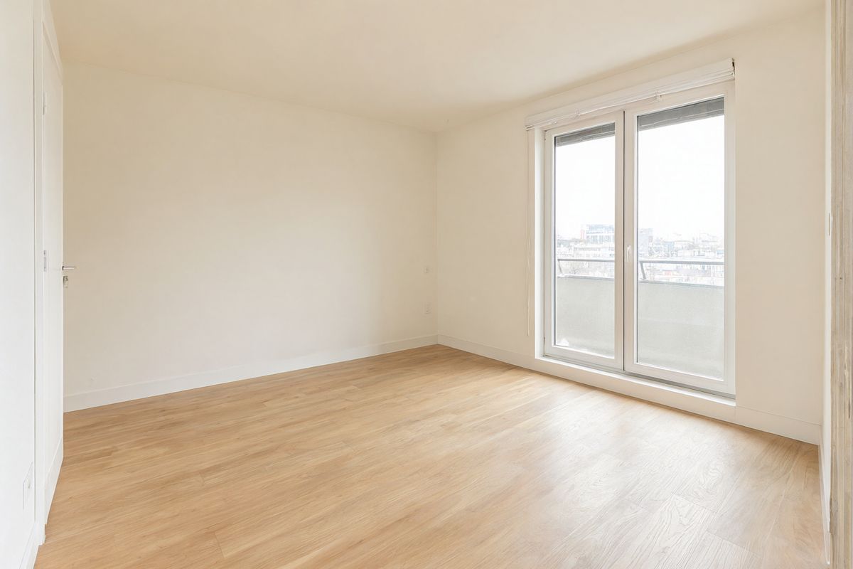 An empty apartment living room with warm white walls, pale oak floorboards, and a floor-to-ceiling window on the right