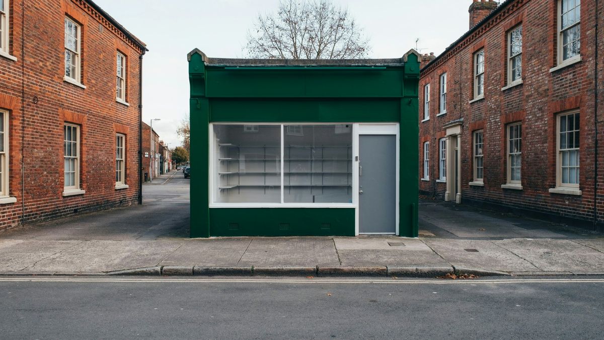 The same shop front with the facade and sign board repainted deep forest green