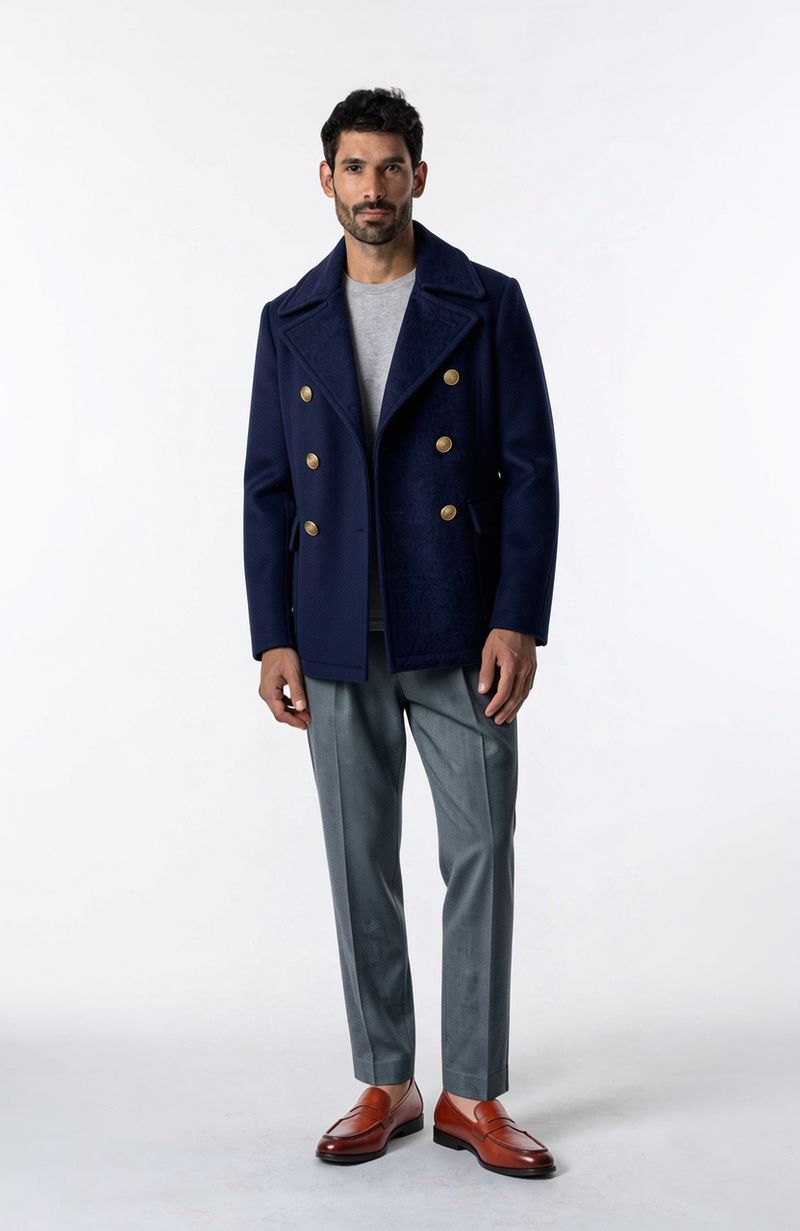 The same man wearing a navy double-breasted peacoat with the same trousers and loafers